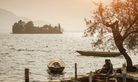 Couple sitting on the edge of Lake Iseo, Italy.