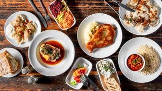 Piles of steaming pierogi crispynbspplacki ziemniaczane  with sour cream and bowls of steaming beetroot soup  theres no...